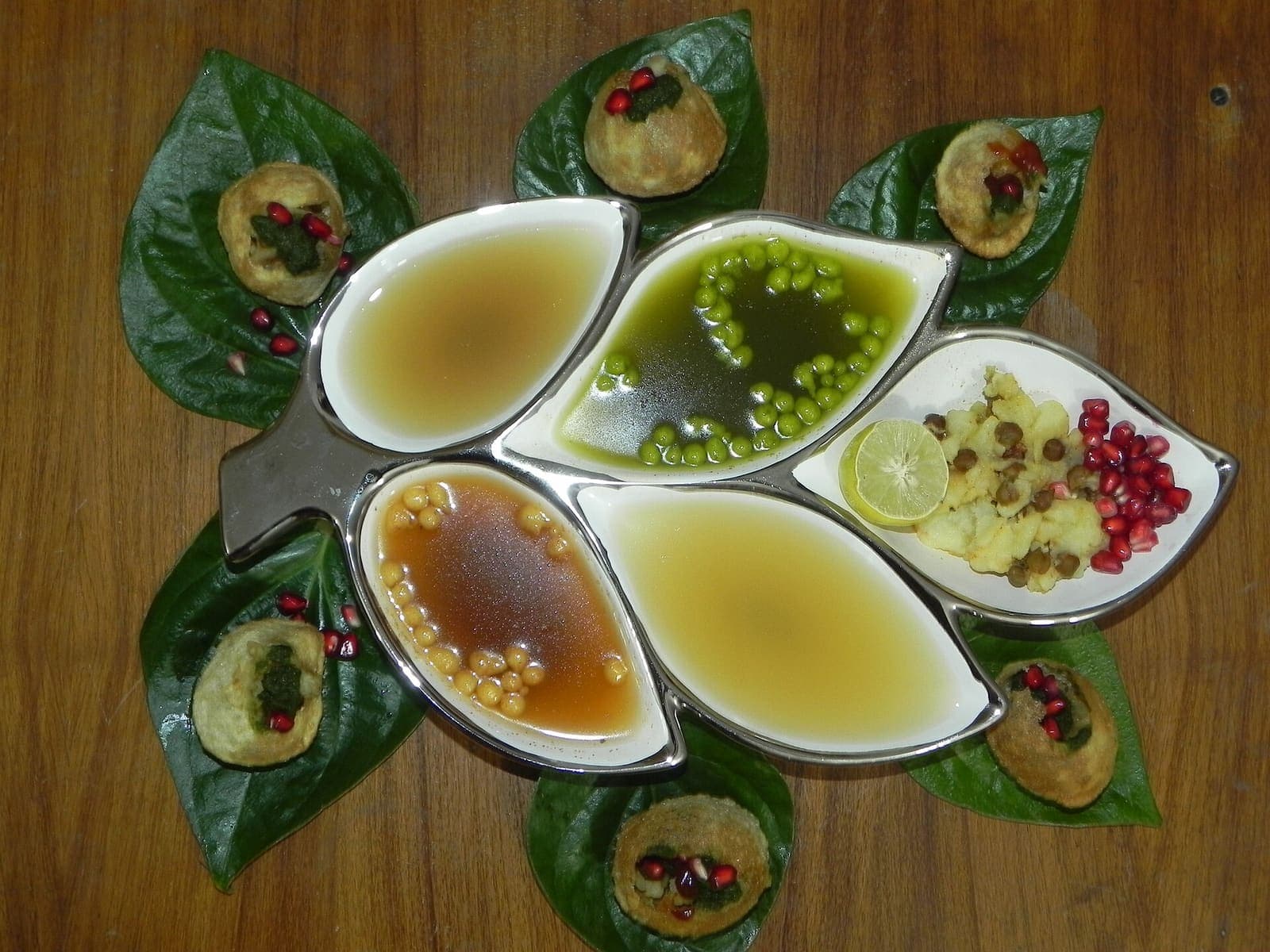 Crisp, hollow gol gappe shells beside small bowls of differently flavoured waters for filling them