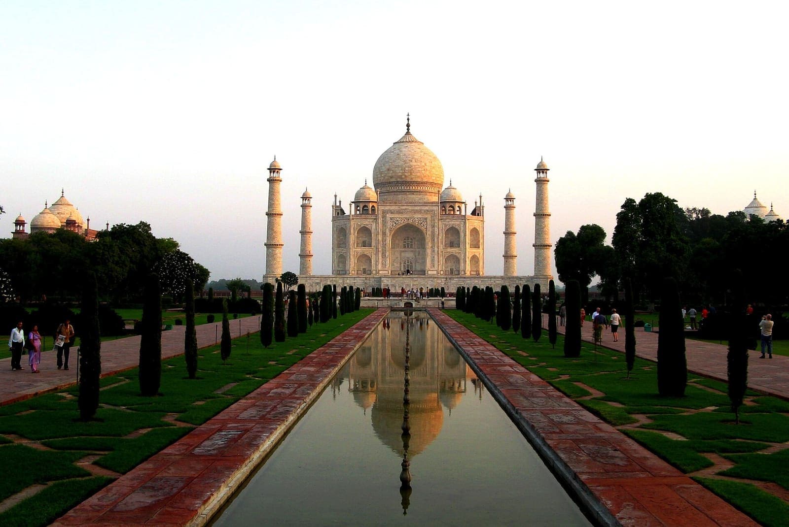 The Taj Mahal in warm early light, reflected in the long water channel between rows of cypress trees