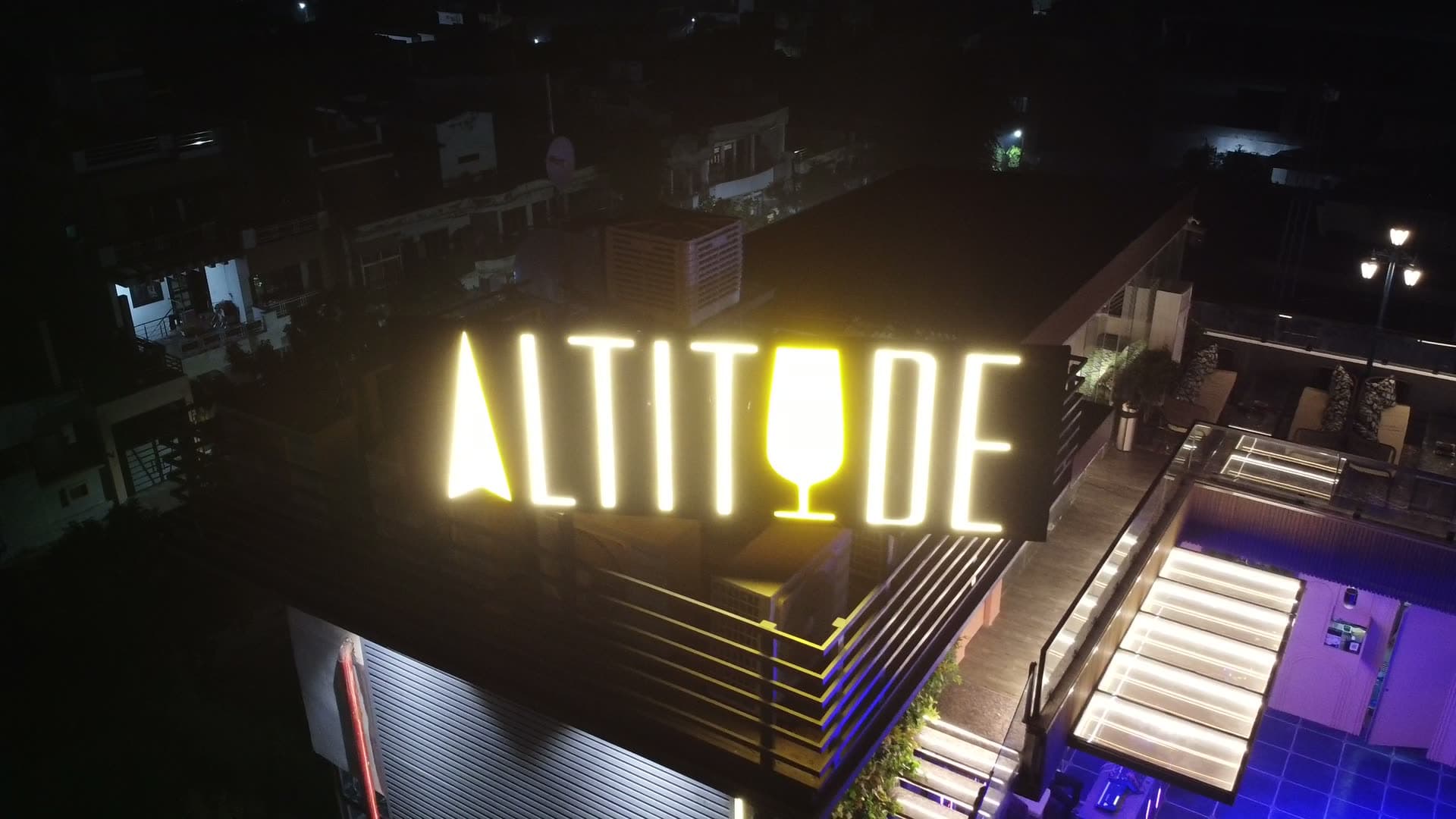 The lit ALTITUDE sign on our rooftop at night, above MG Road 2 in Agra