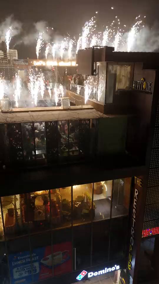 Midnight on New Year’s Eve: fireworks going off all along the edge of the Altitude roof, the gold sign showing through the smoke, Domino’s lit at the street below
